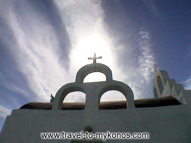 CHURCH BELL, CROSS AND SUN - A traditional bell tower of a small church in Psarou, Mykonos Greece.