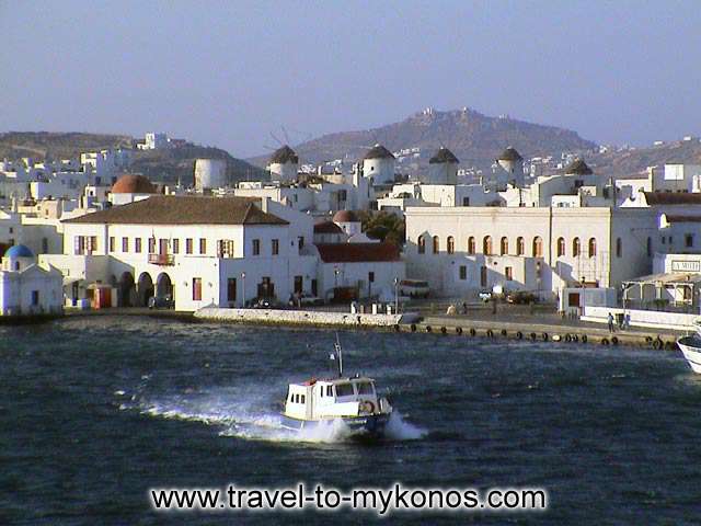 MYKONOS TOWN HALL - The coastal street, the town hall and at back the windmills.