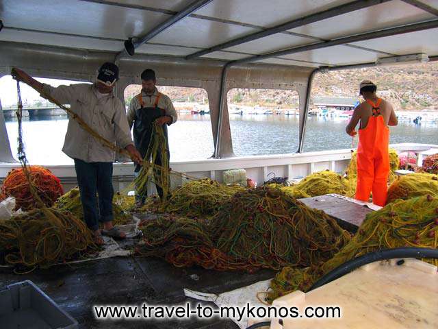 CLEANING NETS - Fishermen preparing the nets on their boat